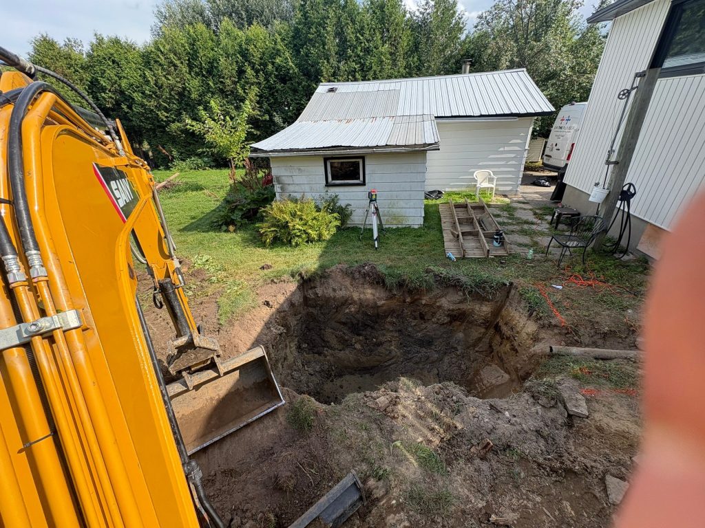 Excavator digging trench for septic tank installation in Ottawa backyard