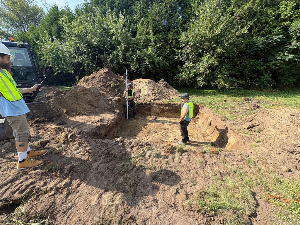 Licensed septic technicians in Ottawa inspecting and measuring excavation for septic system installation